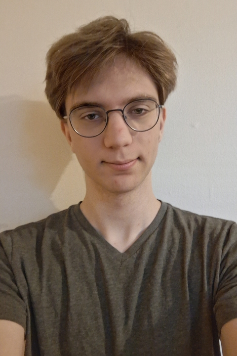 Ari wearing glasses and a gray v-neck t-shirt